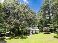 Charming home exterior featuring a well-manicured lawn and mature trees providing ample shade at 6111 Old Monticello Se St, Covington, GA 30014