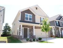 Charming two-story home featuring stone accents, brown siding, complemented by a manicured lawn, and an attached two car garage at 11096 Cornerstone Way, Hampton, GA 30228