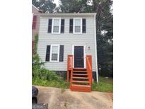 Two-story home featuring gray siding, black shutters, and a black front door with bright orange painted stairs at 2052 Charter Ln, Lithonia, GA 30058