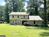 Inviting two-story home with a stone facade and well-maintained lawn, nestled in a serene, wooded setting at 3589 Burlingham Dr, Lithonia, GA 30038