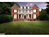 Charming two-story brick home with a white balcony, black shutters, and a manicured lawn at 100 Castlebrook Chase, Tyrone, GA 30290