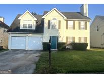 Two-story home with a two-car garage, lawn, and tidy landscaping at 2561 Lancewood Ln, Lithonia, GA 30035