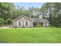 Charming single-story home with a well-manicured lawn and surrounded by lush greenery and mature trees at 8340 Highway 54, Sharpsburg, GA 30277