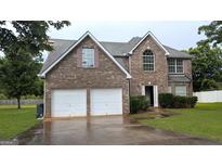 Inviting two-story brick home featuring a two-car garage and a well-maintained lawn at 705 Mustang Ct, Hampton, GA 30228
