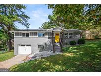Charming gray brick home with a bright yellow front door, surrounded by a lush, green, landscaped yard at 3859 N Camp Creek Sw Pkwy, Atlanta, GA 30331