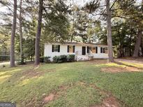 Charming one-story white home with black shutters and a well-maintained front yard with mature shade trees at 10103 Allen Sw Dr, Covington, GA 30014