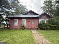 Exterior view of a single-story home with a metal roof, red siding, and a small, well-maintained front yard at 301 Wedowee St, Bowdon, GA 30108