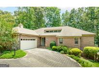 Charming brick home with a two-car garage and lush landscaping along a paved driveway at 1919 Lake Lucerne Sw Way, Lilburn, GA 30047