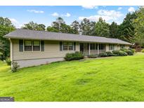 Charming single-story home with lush green lawn, mature trees, and inviting front porch at 110 Mourning Dove S Dr, Fayetteville, GA 30215