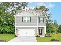 Charming two-story home with gray siding, a white garage door, and a well-manicured lawn at 282 Limestone Circle, Conyers, GA 30013