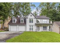 Charming two-story home with a covered front porch, attached two-car garage and a lush green lawn at 539 Riverbirch Trce, Stone Mountain, GA 30087