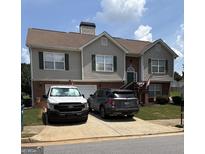 Two-story home with brick and gray siding, green shutters, two cars in driveway, and a small front lawn at 1524 Queen Elizabeth Dr, Locust Grove, GA 30248