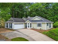 Ranch-style home featuring a two-car garage, mature trees, and a long driveway at 539 Horseshoe Cir, Stockbridge, GA 30281