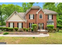 Charming brick home featuring black shutters, complemented by lush landscaping and mature trees at 10044 Point View Dr, Jonesboro, GA 30238