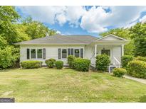 Charming one-story home with white siding, black shutters, and lush green landscaping at 1493 Vesta Ave, Atlanta, GA 30337