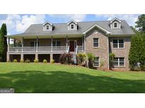 Charming brick home featuring a covered porch, dormer windows, and a well-maintained lawn at 195 Twin Oaks Dr, Hampton, GA 30228