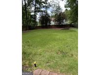 Large, grassy backyard surrounded by trees and a wooden fence at 4887 Winterview Ln, Douglasville, GA 30135