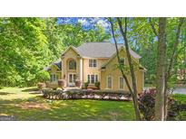Elegant stucco home with manicured landscaping and a lush, green lawn surrounded by mature trees at 551 Lees Mill Rd, Fayetteville, GA 30214