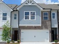 Two-story townhome features a two-car garage, blue shingle siding, and brick accents at 332 Sinclair Ct # 77, Mcdonough, GA 30253