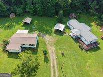 A beautiful aerial view of a farmhouse with a metal roof surrounded by lush greenery at 323 Hollonville Rd, Brooks, GA 30205