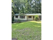Charming home featuring a covered porch, green metal roof, and mature trees surrounding the property at 4688 Brice Dr, Union City, GA 30291
