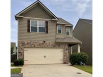 Two-story home featuring a stone facade, attached garage, and neutral siding with decorative shutters at 529 Dasheill Ln, Atlanta, GA 30349