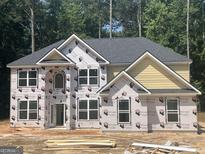 New two-story home with yellow siding, a grey roof, and large windows in a wooded lot at 5565 Hwy 155, Stockbridge, GA 30281