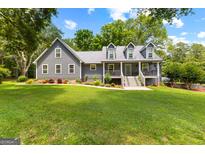Charming gray home features a meticulously manicured lawn, colorful flowerbeds, and dormer windows at 152 Bear Creek Rd, Moreland, GA 30259