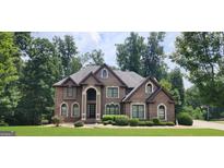 Inviting brick home featuring manicured landscaping, arched windows and an impressive entryway at 8260 Equinox Ln, Fairburn, GA 30213
