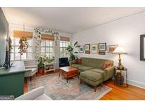 Bright living room with an olive sofa, hardwood floors, and lush green plants at 1166 Virginia Avenue Northeast Ne Ave # 8, Atlanta, GA 30306