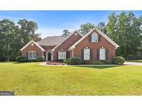 Charming single-story red brick home features manicured lawn and lush landscaping at 1032 Shumard Ln, Mcdonough, GA 30252