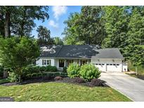 Charming home featuring a well-manicured lawn, complemented by lush landscaping and a convenient two-car garage at 591 Clubwood Ct, Marietta, GA 30068