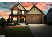 Charming two-story brick home with a covered front porch and manicured lawn at sunset at 6665 Flagstone Ct # 918, Cumming, GA 30028