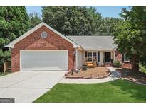 Charming brick home with a well-manicured lawn, swing, and attached garage, perfect for curb appeal at 1535 Smoke Hill Dr, Hoschton, GA 30548