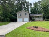 Charming two-story home with a well-manicured lawn and a long, paved driveway at 7562 Asbury Manor, Lithonia, GA 30058