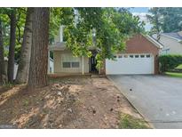 Charming home with a two-car garage and partially obscured by mature trees at 686 Shore Ln, Lithonia, GA 30058