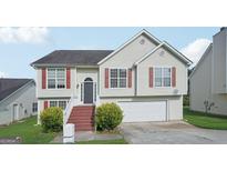 Charming two-story home featuring light siding, red shutters, an attached garage, and well-maintained landscaping at 4738 Golod Way, Lithonia, GA 30038