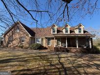 Charming brick home featuring dormer windows and a covered front porch for relaxing outdoor living at 291 Morgan Mill Rd, Brooks, GA 30205