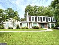 Charming home with a beautiful lawn, walkway, and mature trees providing shade at 308 Larkspur Turn, Peachtree City, GA 30269