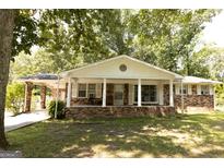 Charming brick home features a covered porch, well-maintained lawn, and mature trees at 1112 Mealor Rd, Lawrenceville, GA 30043