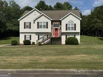 Inviting two-story home with a well-manicured lawn, red front door, and decorative stone accents at 51 Estates Dr, Villa Rica, GA 30180