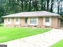 Charming brick home with a well-maintained lawn, complemented by a light green front door and traditional shuttered windows at 10178 Top Tree Ct, Jonesboro, GA 30238