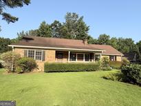 Charming brick home featuring a well-maintained front yard with lush landscaping and a covered front porch at 601 Clubland Se Cir, Conyers, GA 30094