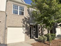 Brick two-story townhome with a single car garage and a well-manicured lawn at 1650 Larkspur Trl, Conyers, GA 30012