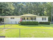 Charming single-story home featuring a quaint porch, green lawn, and fenced yard at 340 Loblolly Rdg, Locust Grove, GA 30248