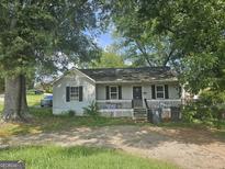 Cozy one-story home featuring a welcoming front porch and ample shade trees at 443 Walker St, Villa Rica, GA 30180