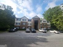 Traditional-style apartment building with brick facade, and mature trees set against a partly cloudy sky at 3219 Fairington Dr, Lithonia, GA 30038