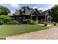 Charming home featuring a landscaped front yard, stone accents, and a welcoming covered entry at 1051 Lake Rutledge Rd, Rutledge, GA 30663