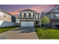 Two-story home featuring stone accents, a two-car garage, a green lawn, and neutral colored siding at 2384 Hastings Manor Ln, Hampton, GA 30228
