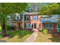 Charming brick townhome with well-maintained lawn, walkway, and mature shade trees at 398 Patrick Henry Ct, Riverdale, GA 30274